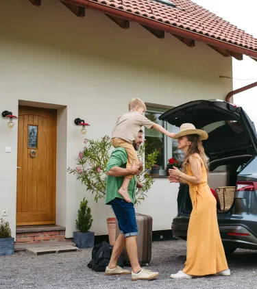 a family of three with road trip travel insurance arrives to their vacation rental and unloads their electric car