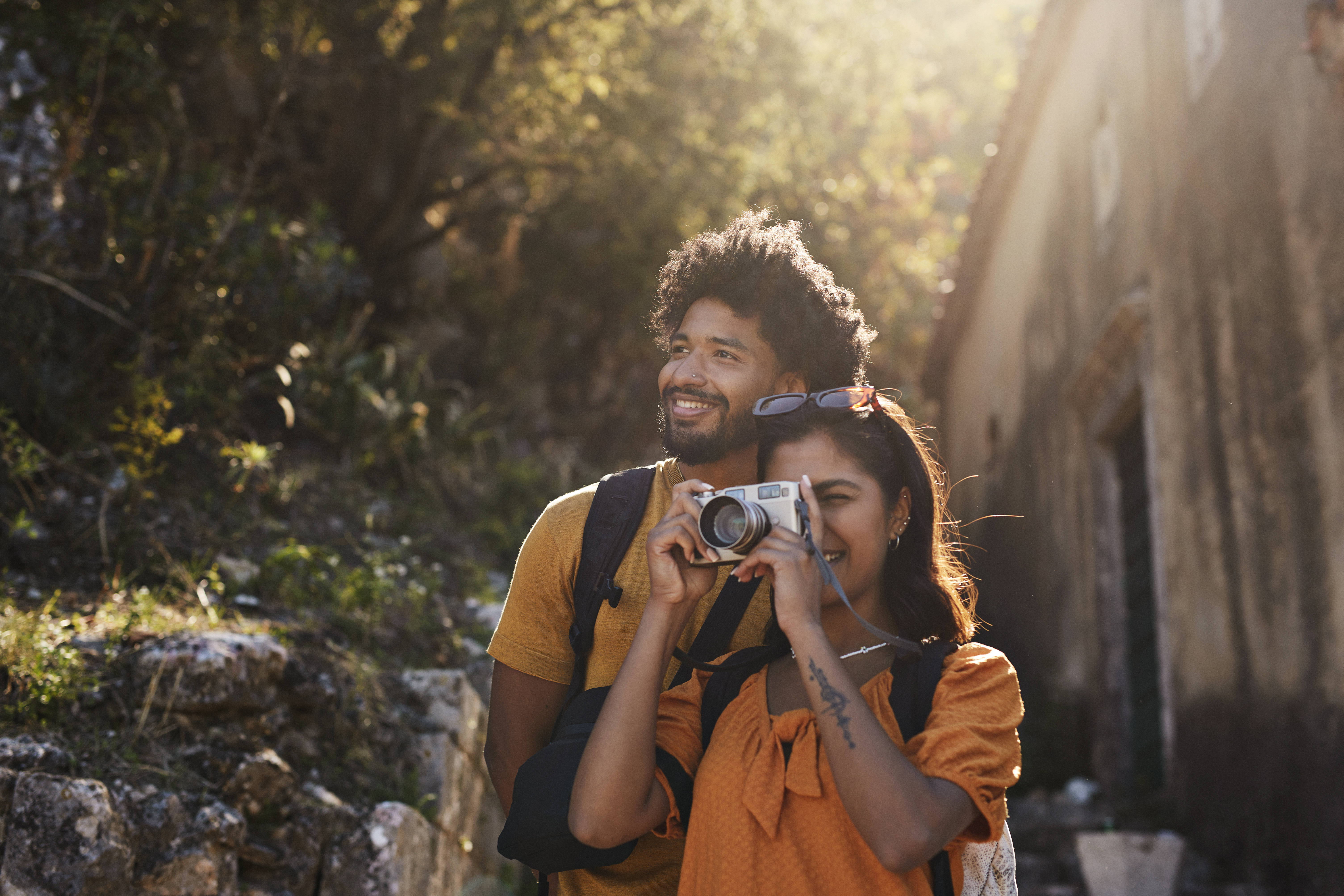 a young man and woman tour outdoors with their camera after looking up, "Is travel insurance worth it?"