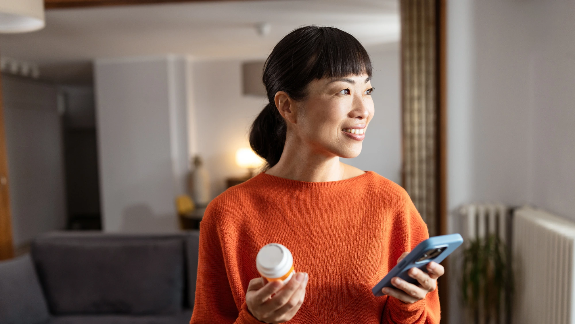 a middle-aged woman holds her phone and one and in her other a prescription on vacation