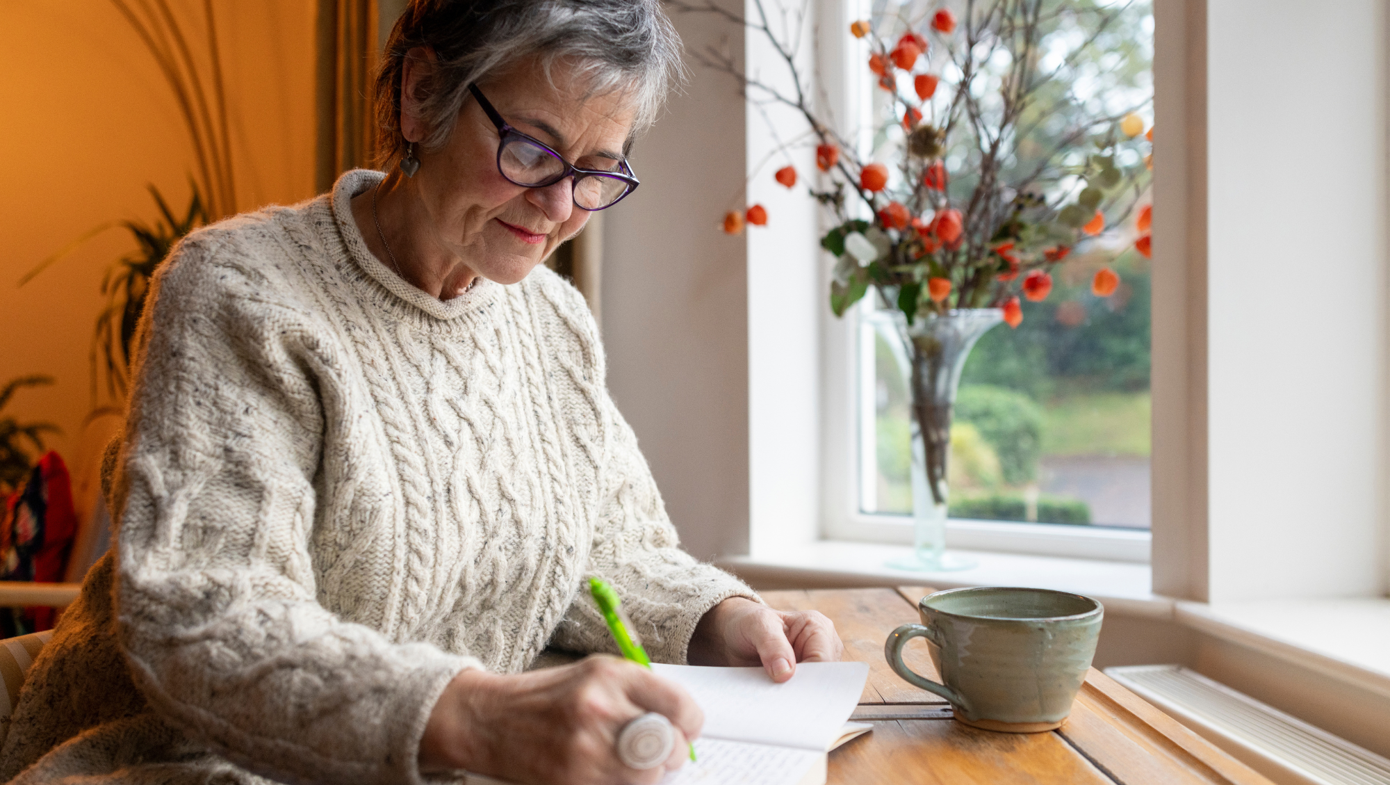 an older woman writes down her travel insurance checklist on a notepad