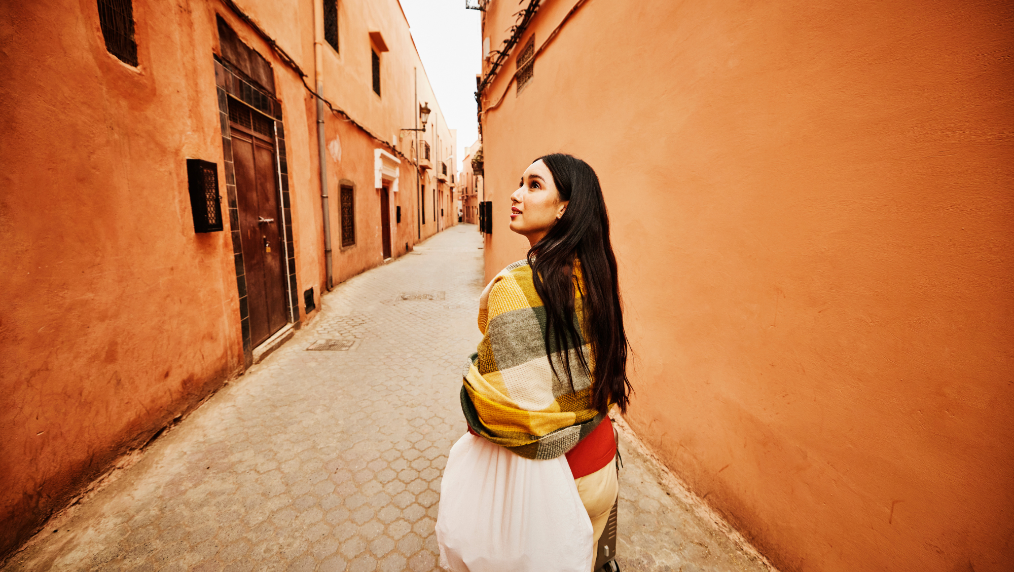 a woman walks through a historic alleyway on vacation after researching "Is travel insurance worth it?" 