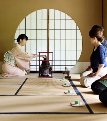 several travelers, with travel insurance for cultural trips, attend a traditional Japanese tea ceremony
