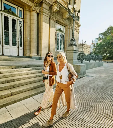 two female travelers with travel insurance for city trips visit a historic landmark on vacation