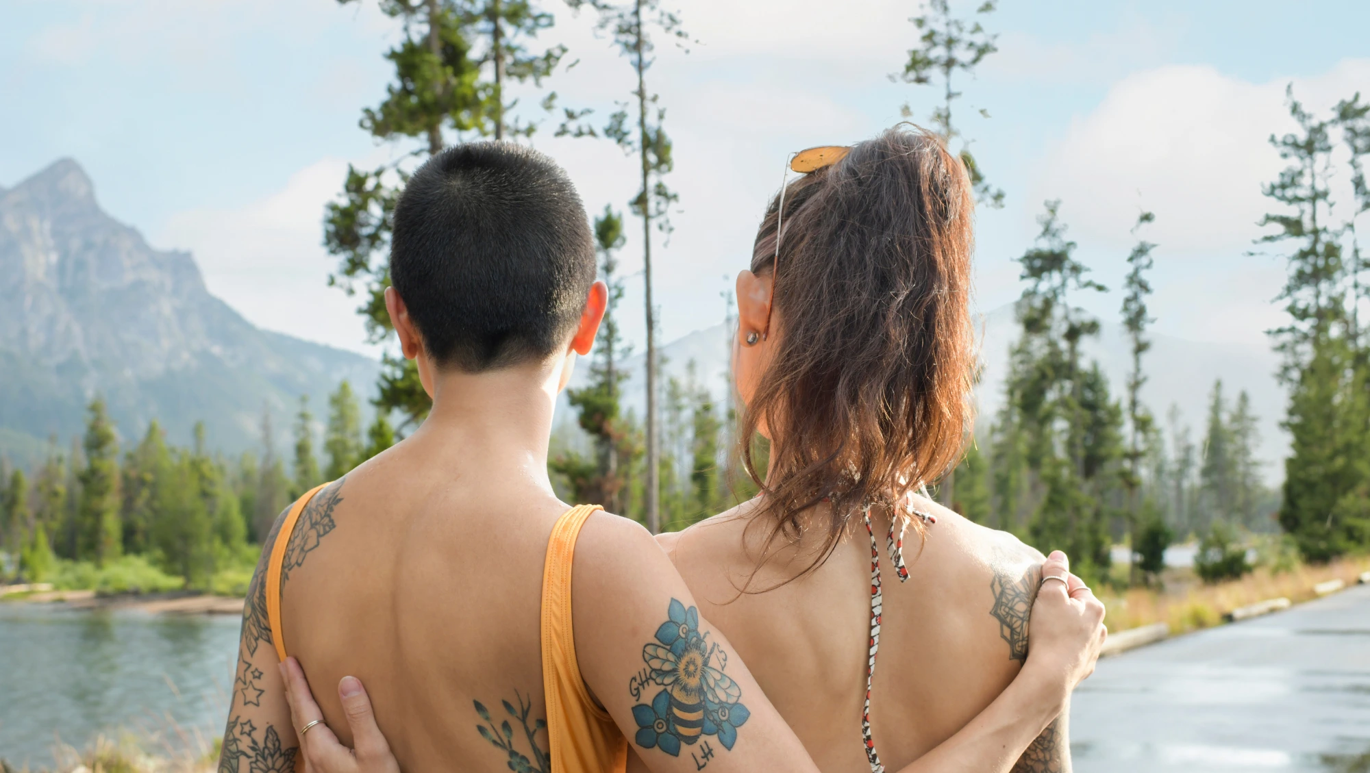 two partners embrace in front of a lake after deciding to beat their travel anxiety and go on vacation