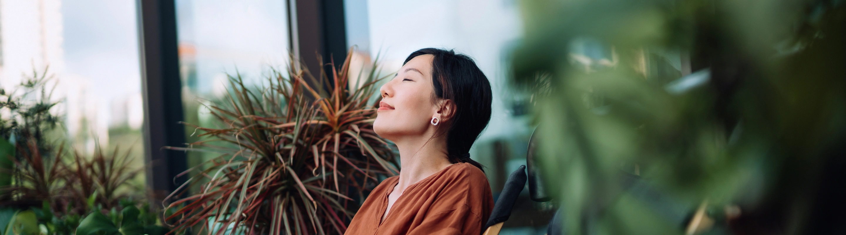 a middle-aged woman with travel insurance for wellness retreats relaxes in a garden lounge chair in an orange dress