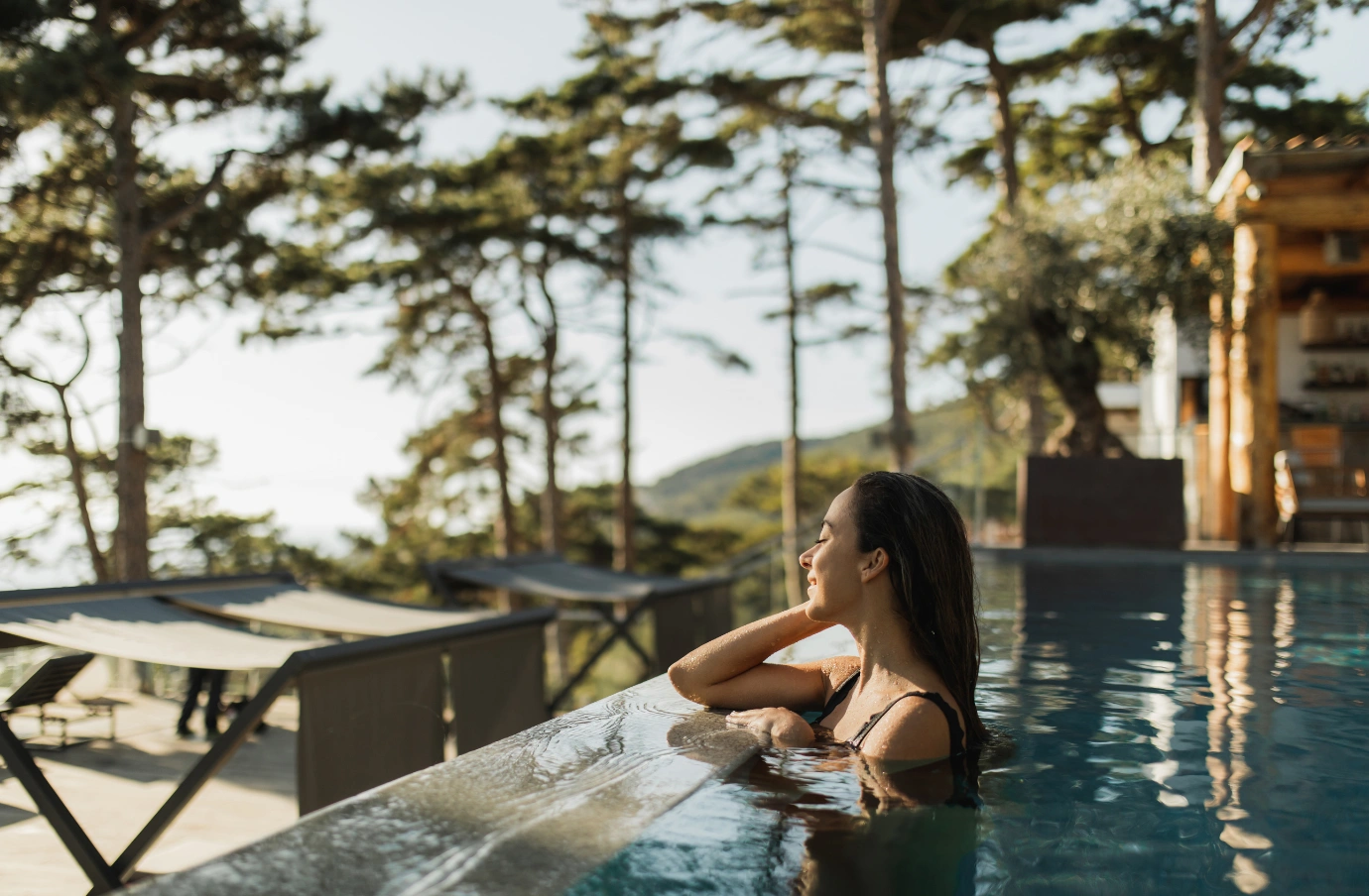 a young woman with travel insurance for wellness retreats relaxes in an infinity pool in a forest 