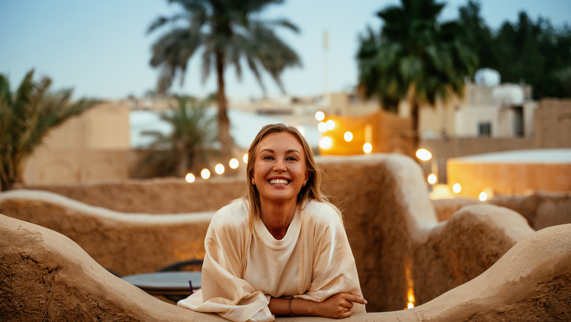 a woman smiles on vacation in the Middle East after looking up, "Does travel insurance cover wars and terrorism?"
