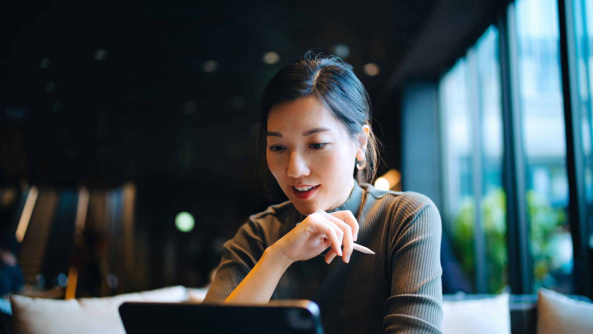 a young woman goes through her travel insurance checklist on her tablet in a modern lobby