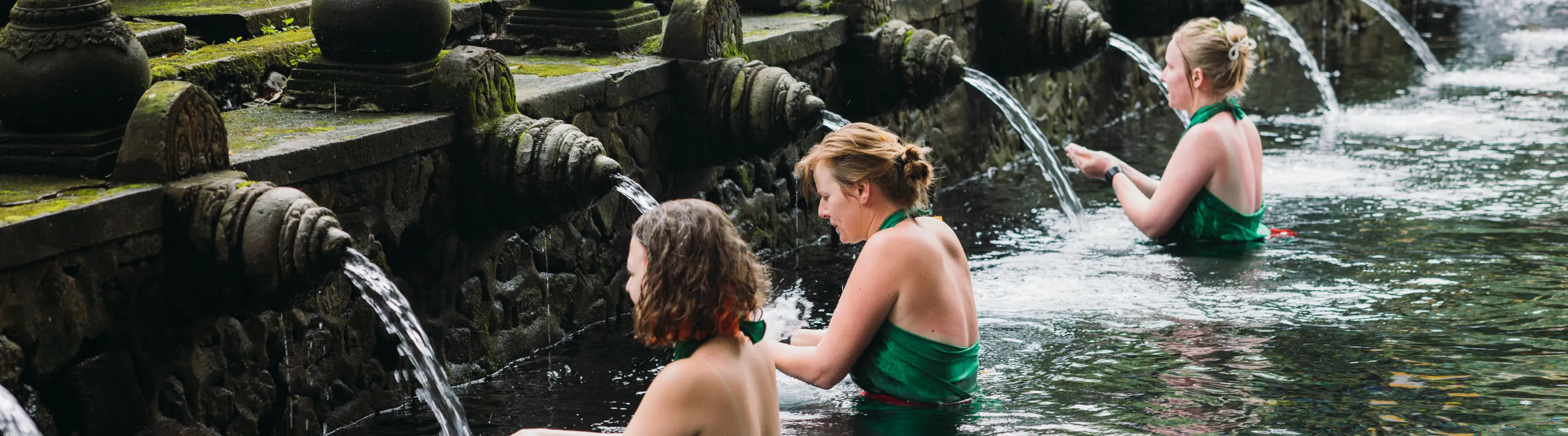 three women participate in a temple water purification ritual, insured with travel insurance for religious trips