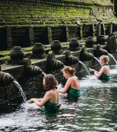 three women participate in a temple water purification ritual, insured with travel insurance for religious trips