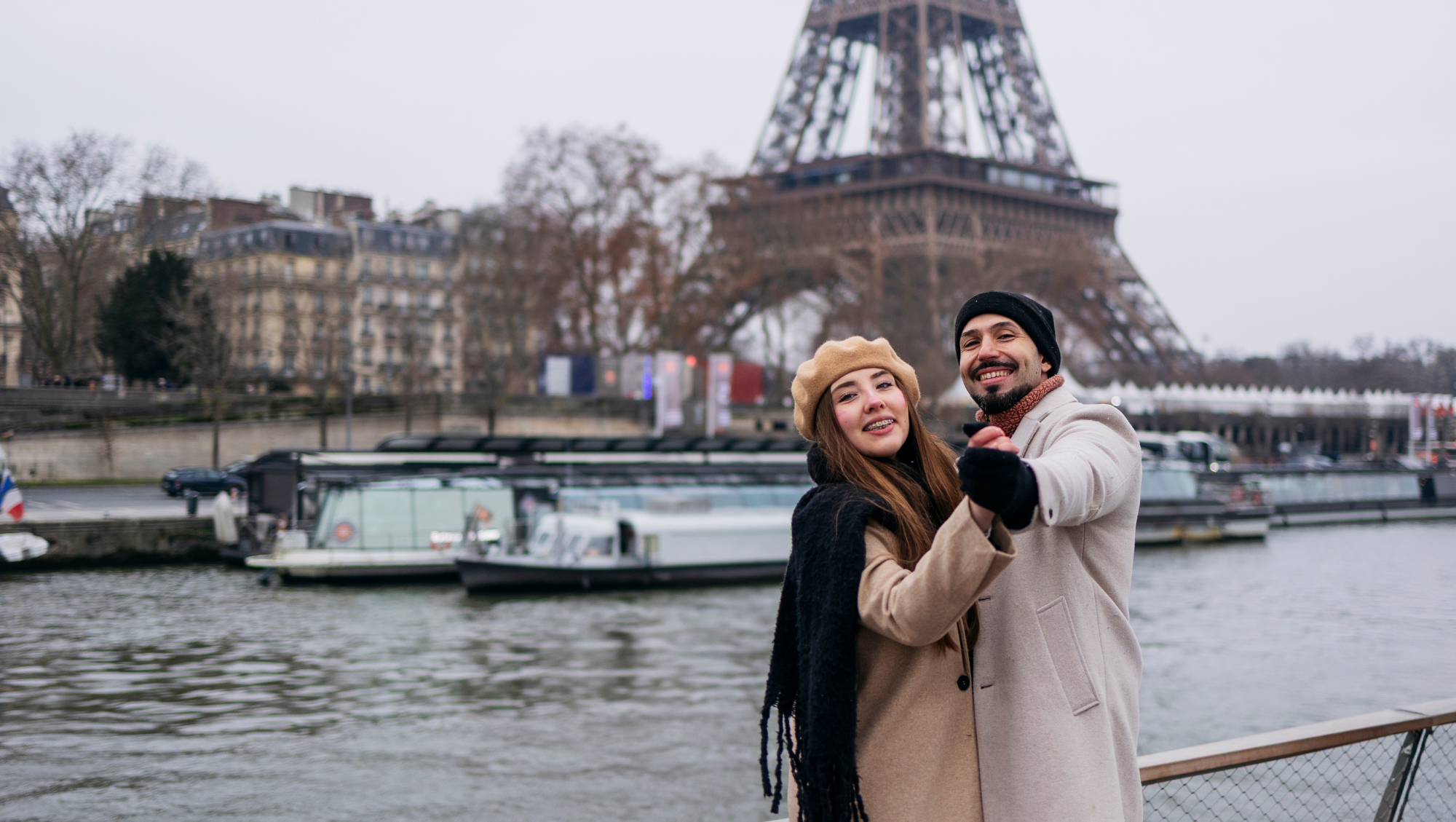 a couple holds hands near the Eiffel Tower in Paris on vacation after researching, "Does travel insurance cover terrorism?"