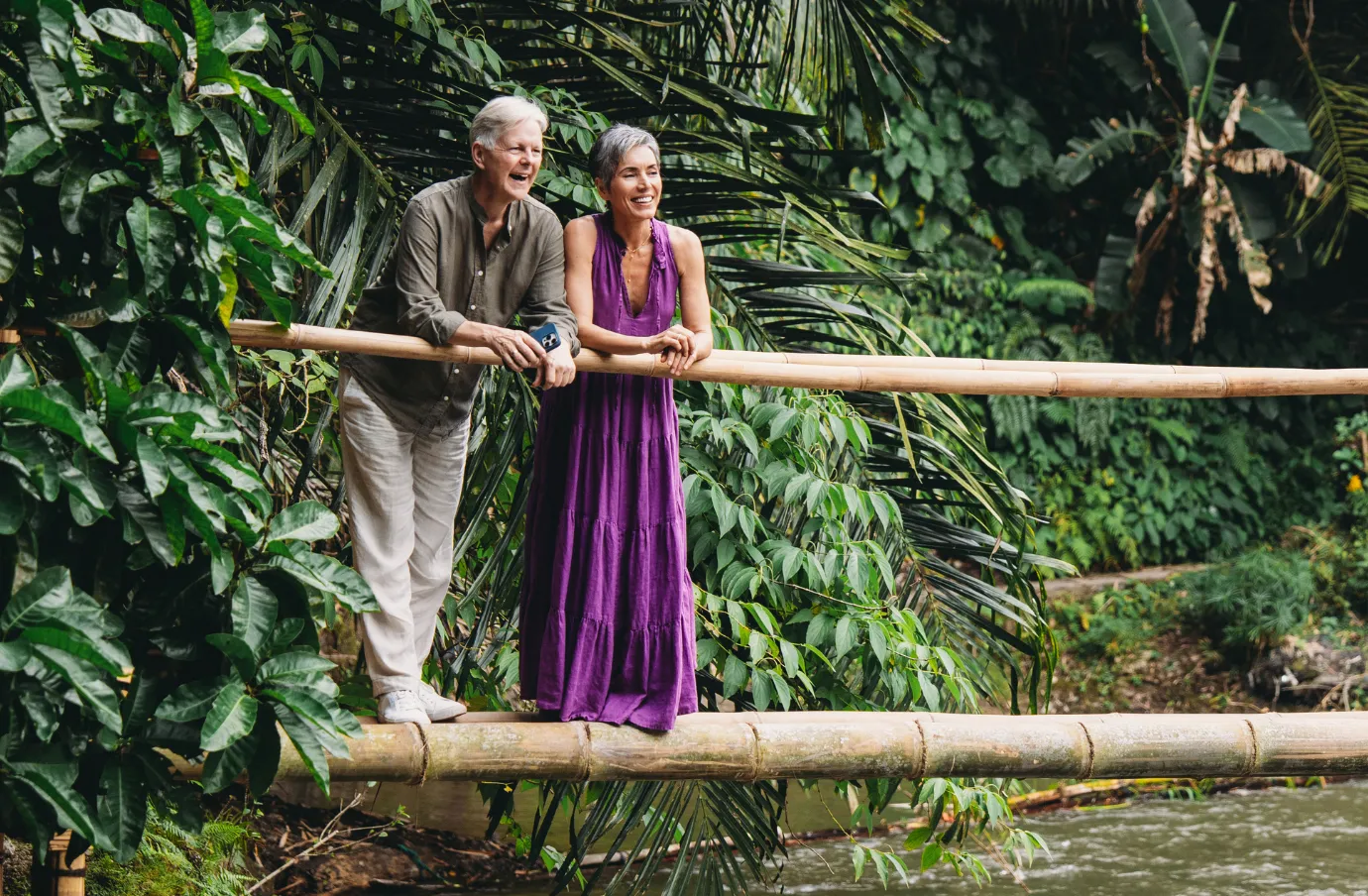 an older couple stands on a bamboo bridge in the jungle, insured with travel insurance for Bali