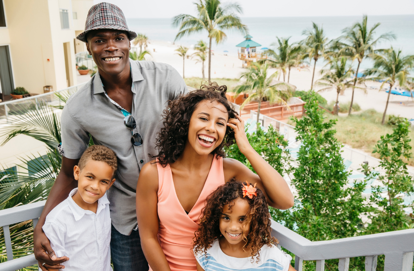 a family of four smiles on their beach resort vacation, insured with travel insurance for Florida