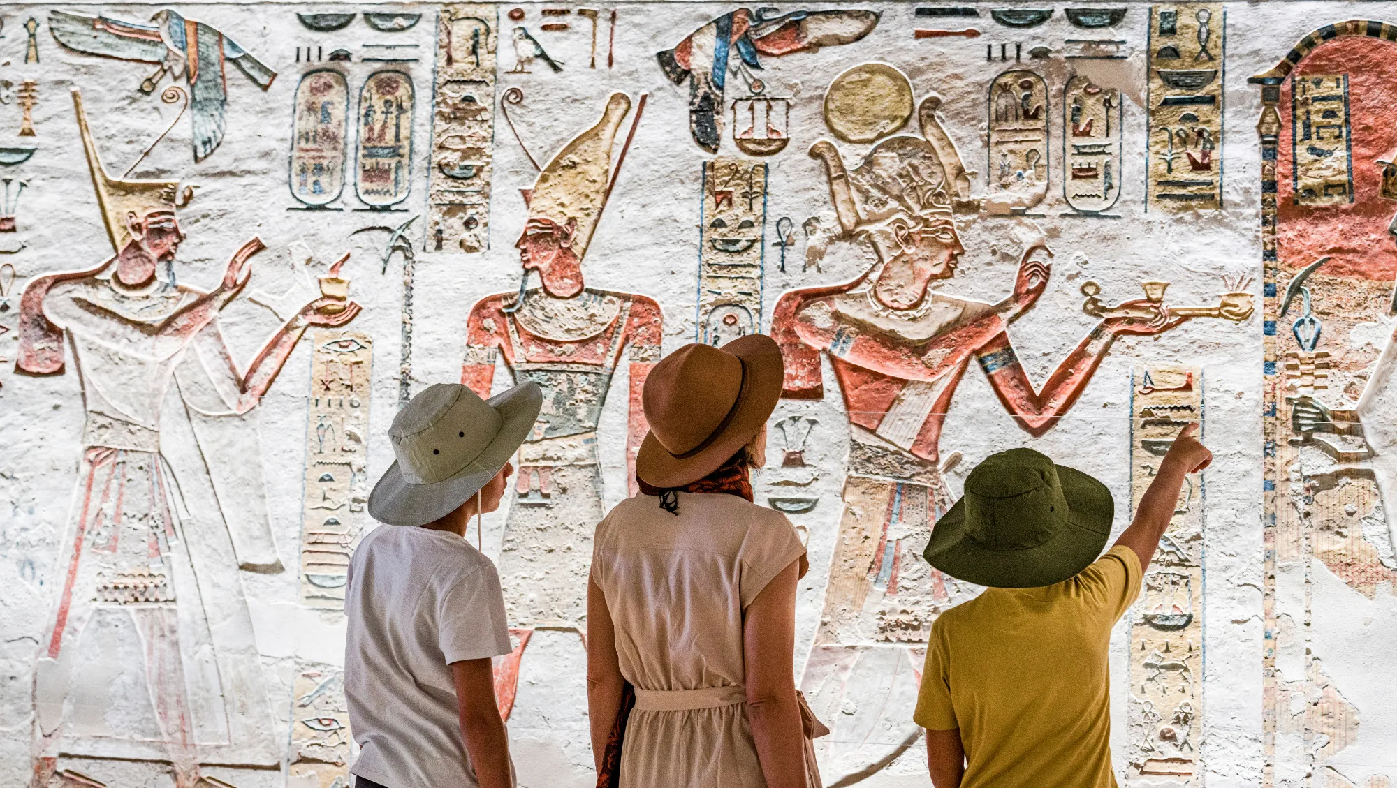 a family views ancient Egyptian hieroglyphs on vacation after asking, "Is travel insurance worth it?"