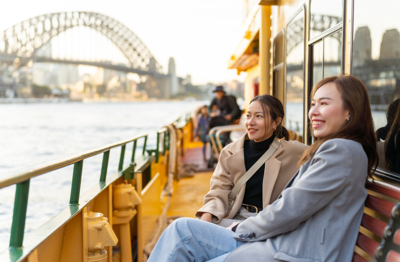 two young, female friends enjoy a Sydney Harbour ferry ride, insured with travel insurance for Australia 