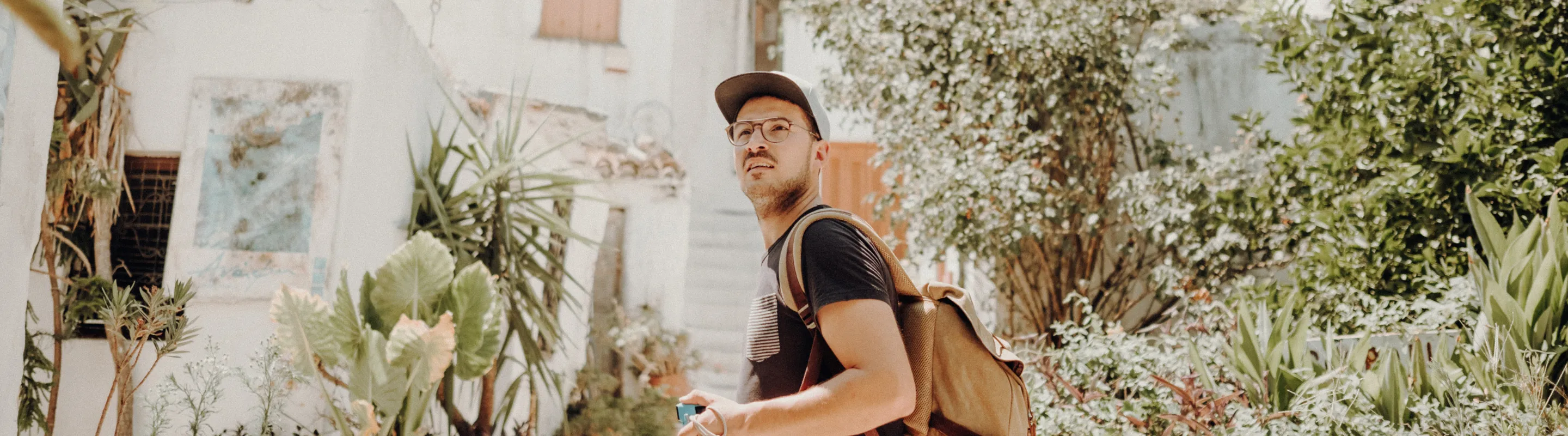 a young man walks through a neighborhood in Athens on vacation, insured with travel insurance for Greece 