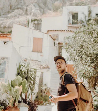 a young man walks through a neighborhood in Athens on vacation, insured with travel insurance for Greece 