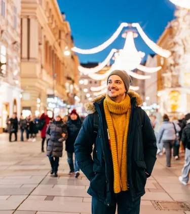 a man walking through Graben, Vienna, as night falls, insured with travel insurance for Austria 