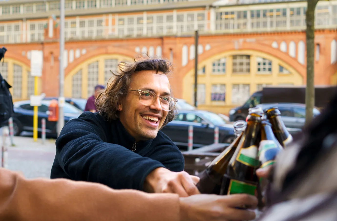 a young man with travel insurance for Germany toasts his beer with friends on vacation