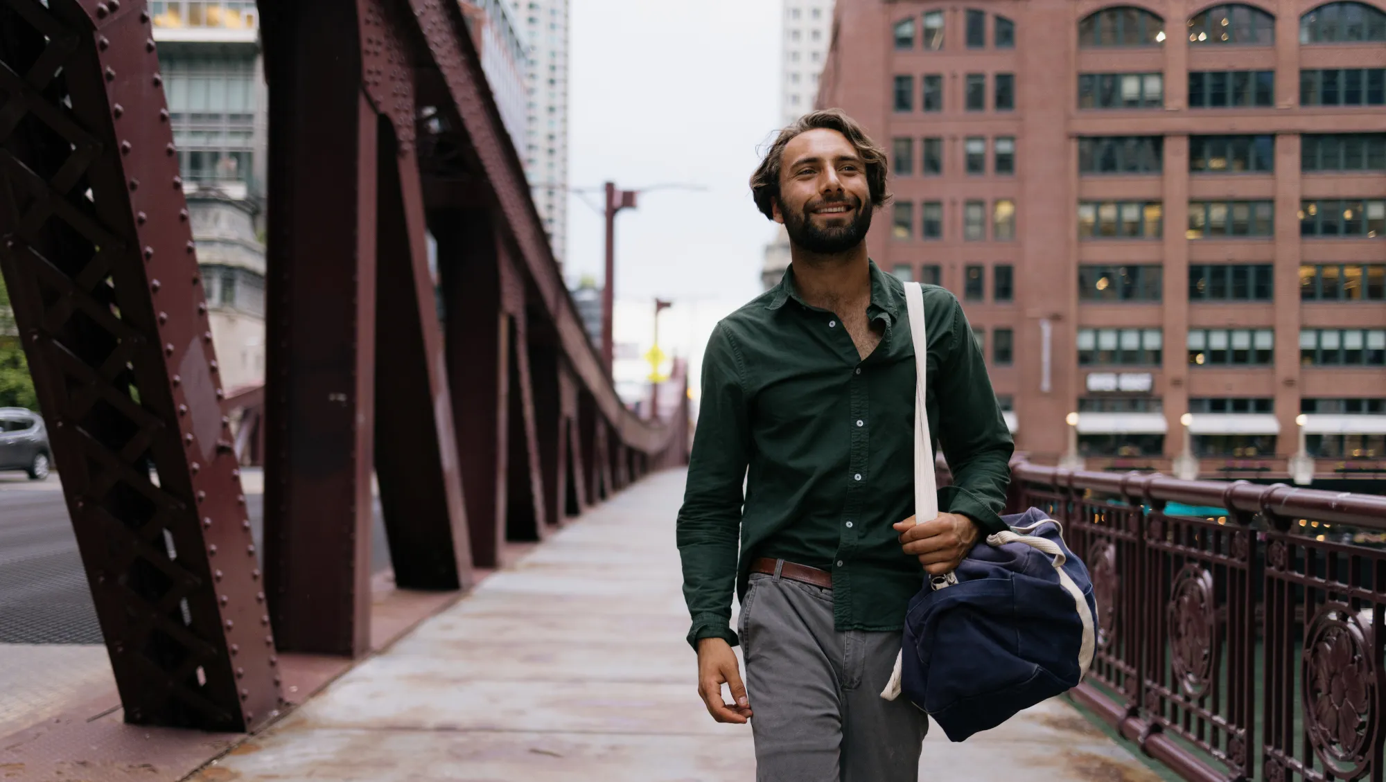a man walks across a red steel truss bridge in Chicago after asking, "Is travel insurance worth it?"