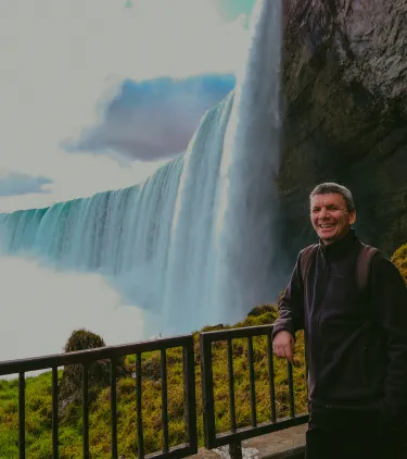 a male tourist smiles on a lookout point at Niagara Falls, insured with travel insurance for Canada