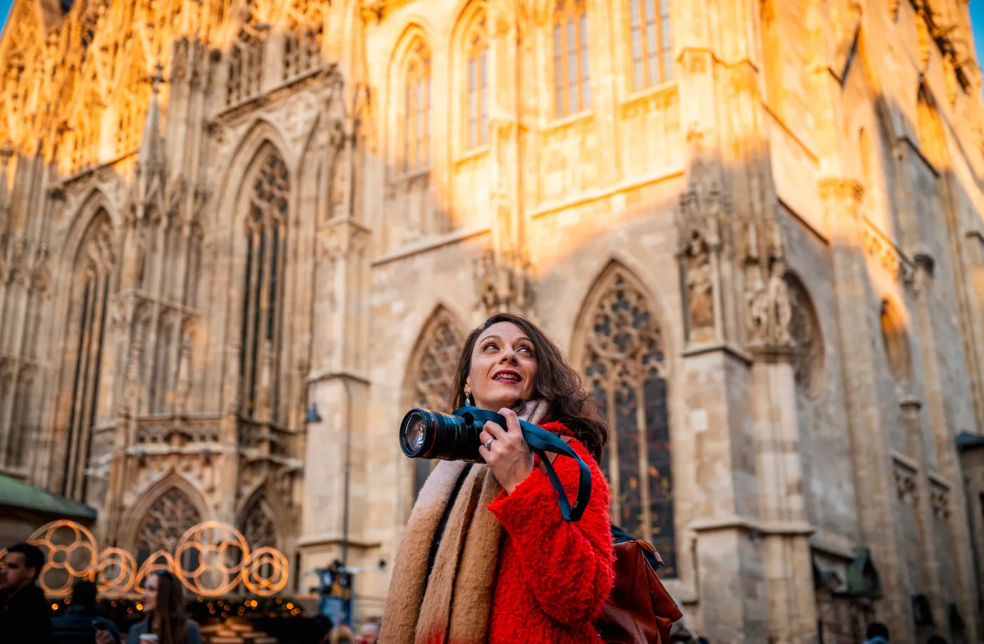 a woman traveler holds her camera outside a cathedral in Vienna, insured with travel insurance for Austria