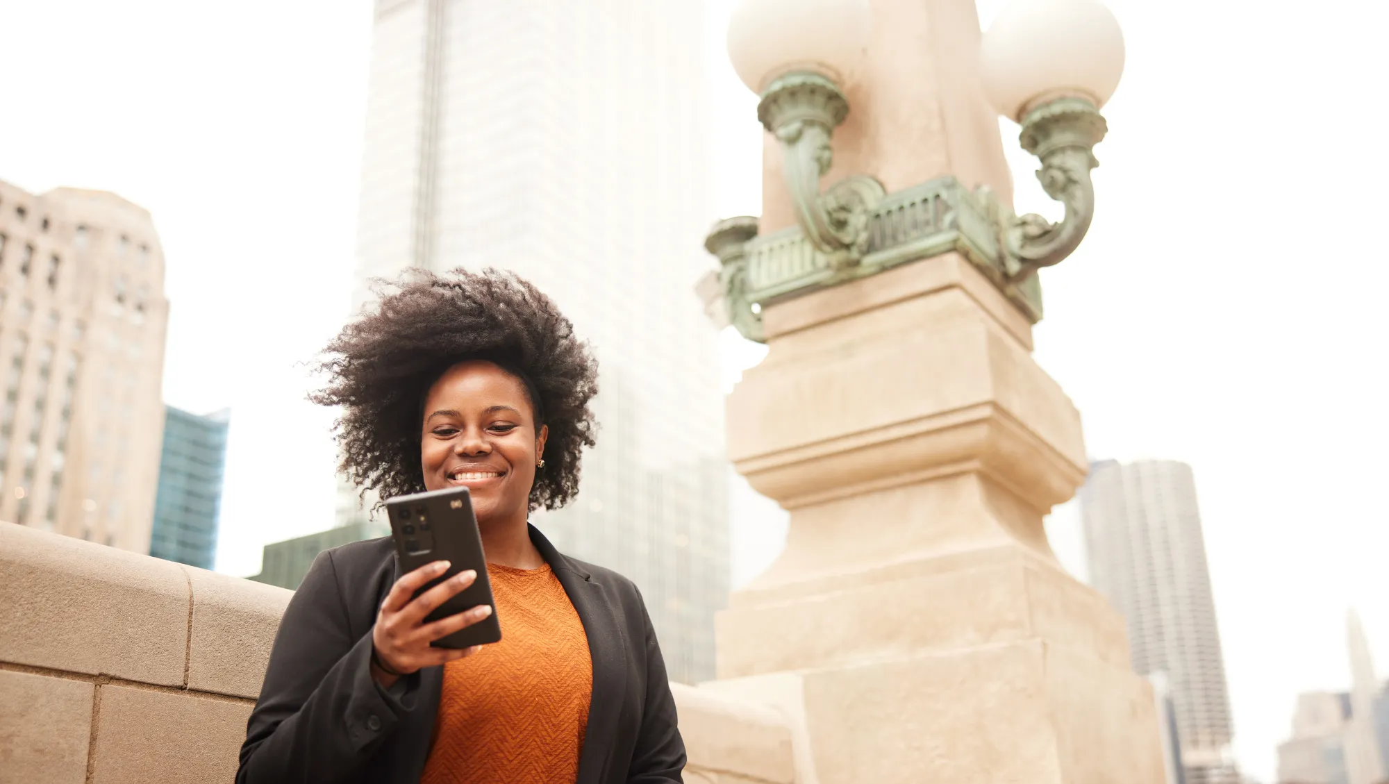 a woman uses her phone on a windy day in Chicago, insured with tornado insurance 