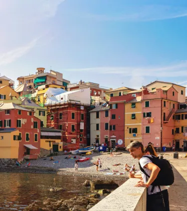 two young travelers admire the waterfront in Boccadasse, Italy, insured with travel insurance for Europe