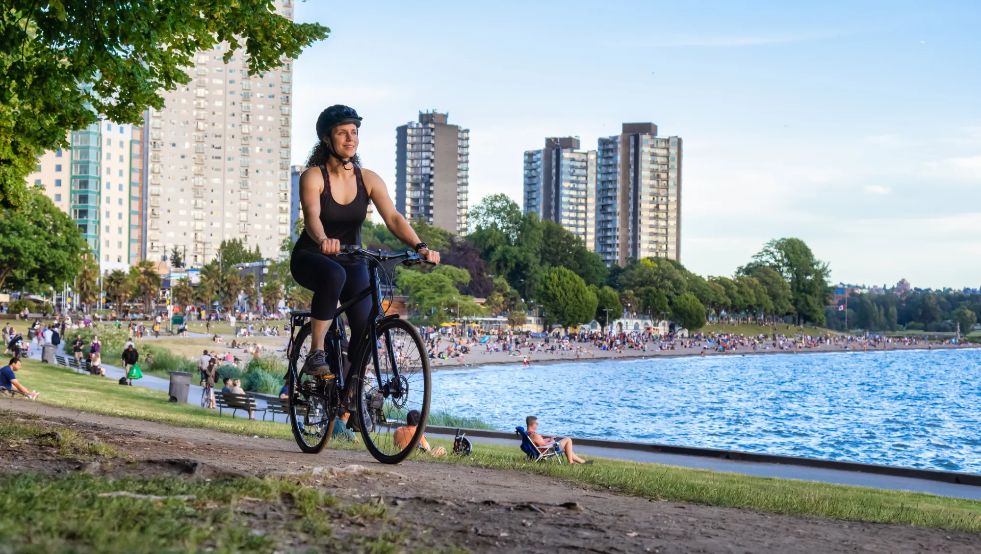 a woman tourist bikes the waterfront in Stanley Park, Vancouver, after researching, "Is travel insurance worth it?"