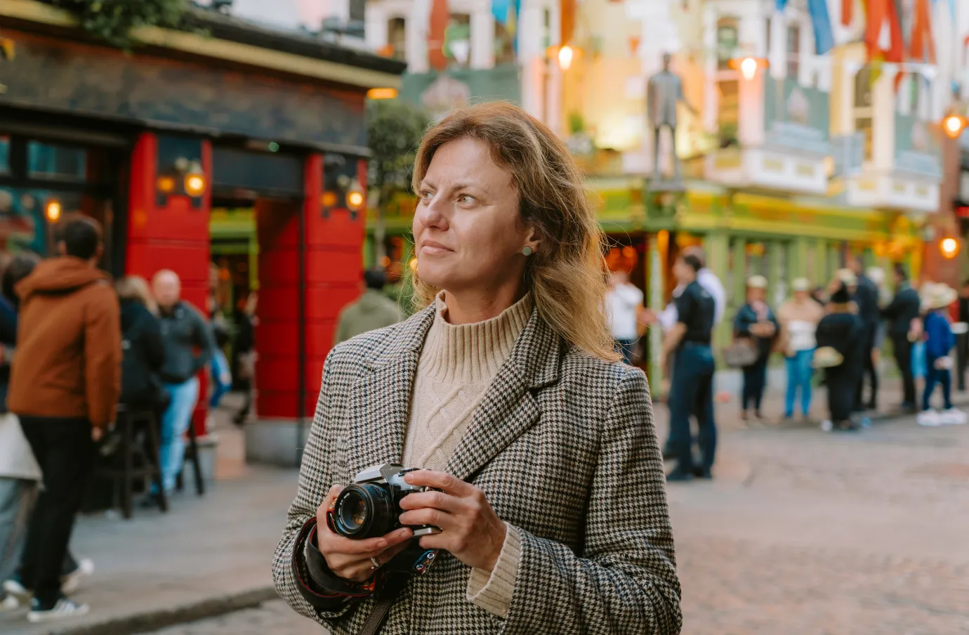 a middle-aged woman holds a camera as she walks through downtown Dublin, insured with travel insurance for Ireland 