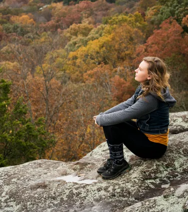 a woman sits on a rock while hiking the Garden of Gods, insured with travel insurance for Illinois
