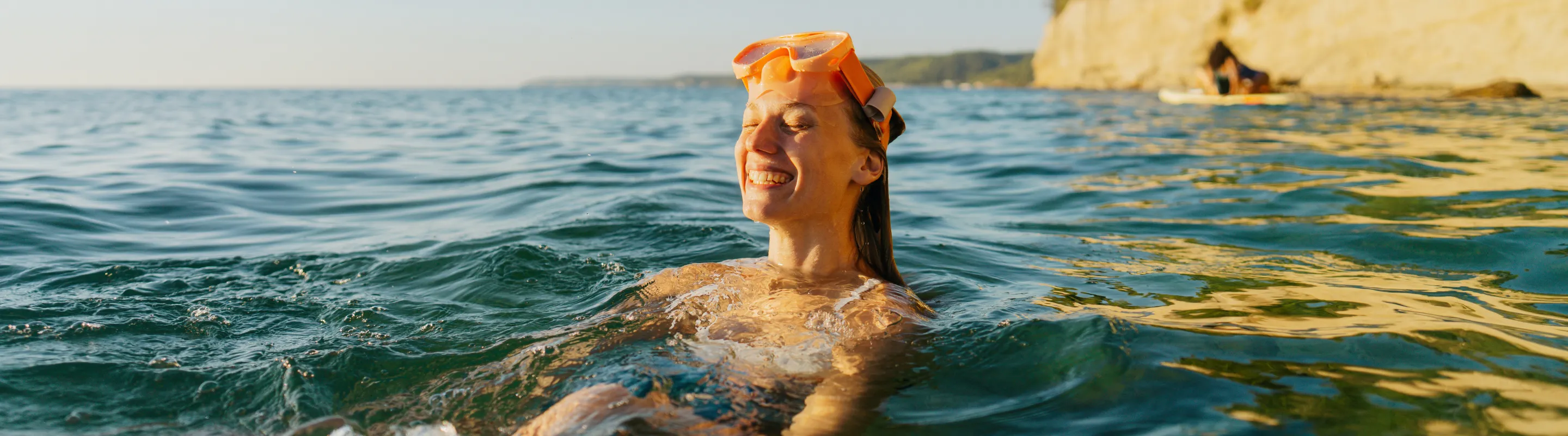 a woman wears snorkel gear in the Mediterranean Sea, insured with travel insurance for Greece 