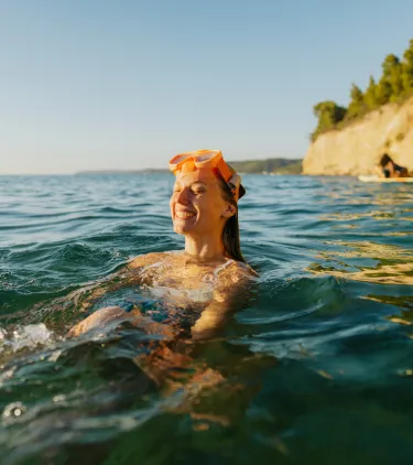a woman wears snorkel gear in the Mediterranean Sea, insured with travel insurance for Greece 