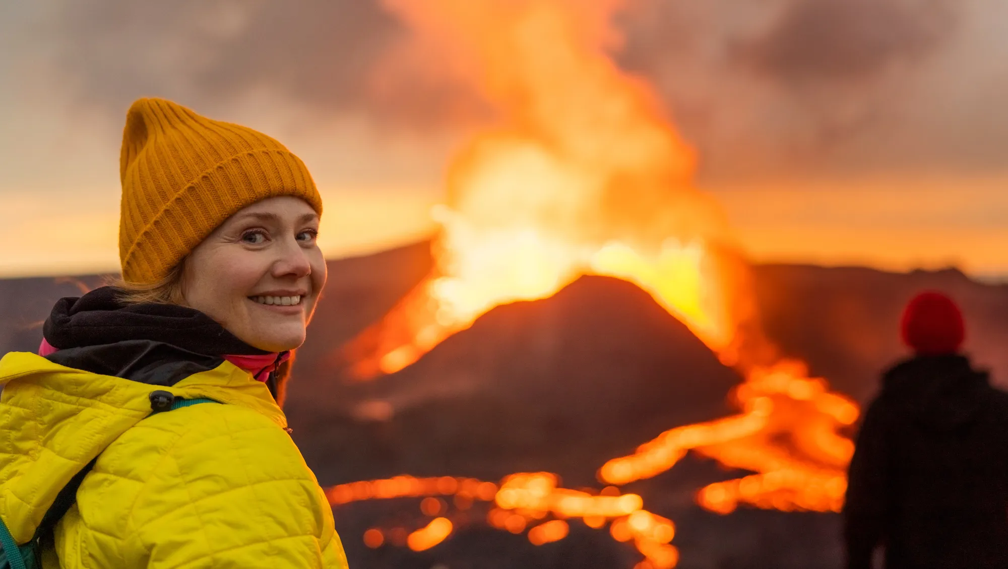 a woman with volcano travel insurance views an active volcano on a guided tour in Iceland