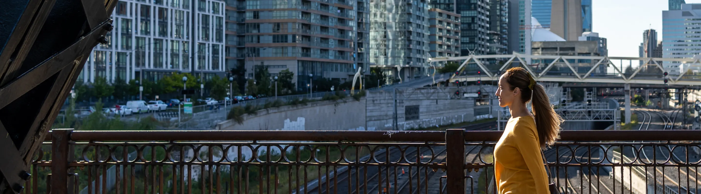 a woman in a yellow shirt walks through downtown Toronto, insured with travel insurance for Canada 