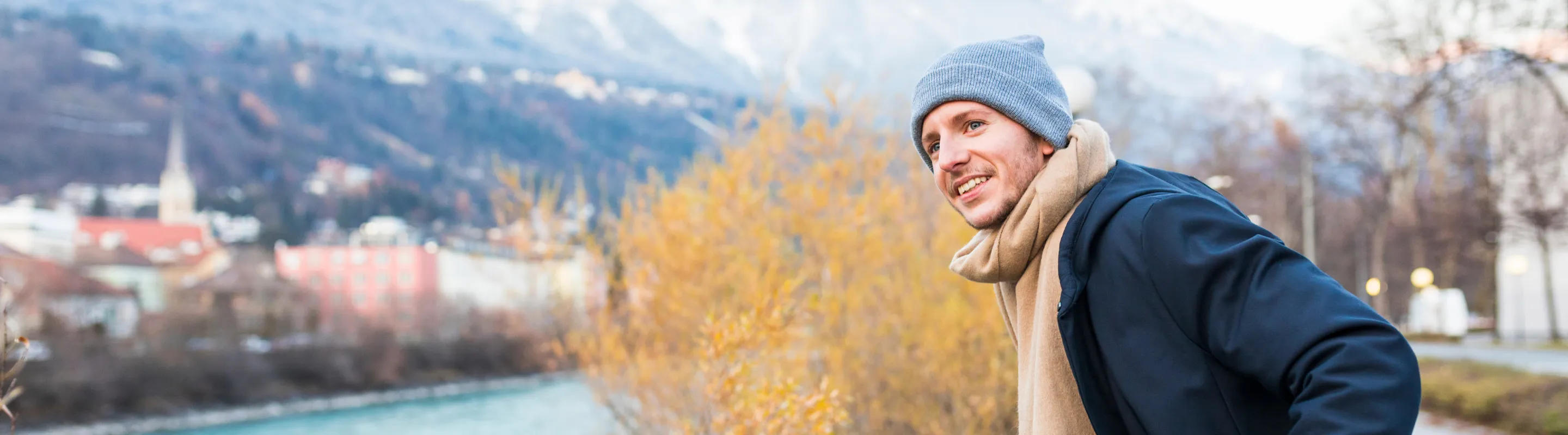 a young man with travel insurance for Austria overlooks the scenic town of Innsbruck in winter clothes 