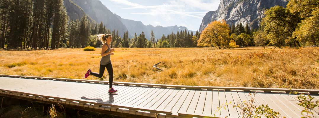 Young woman running on a boardwalk in Yosemite after reading a United States travel guide