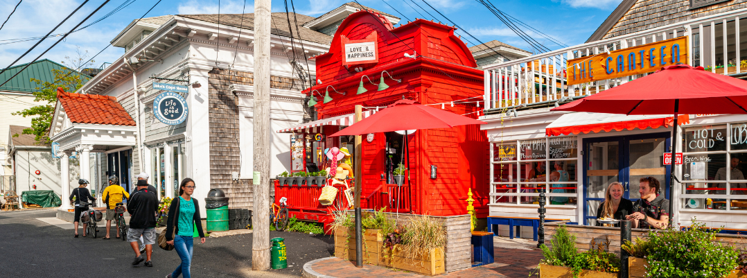 Young woman walking by quaint shops on the street in Cape Cod, one of the best places to travel as a solo female in the U.S.