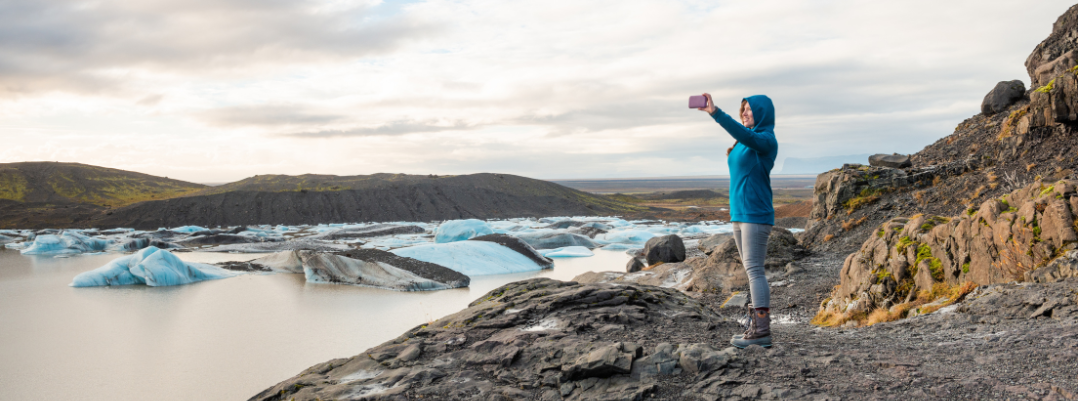 Woman taking a selfie at a glacier lagoon in Iceland, one of the best places to travel as a solo female in the U.S. and more