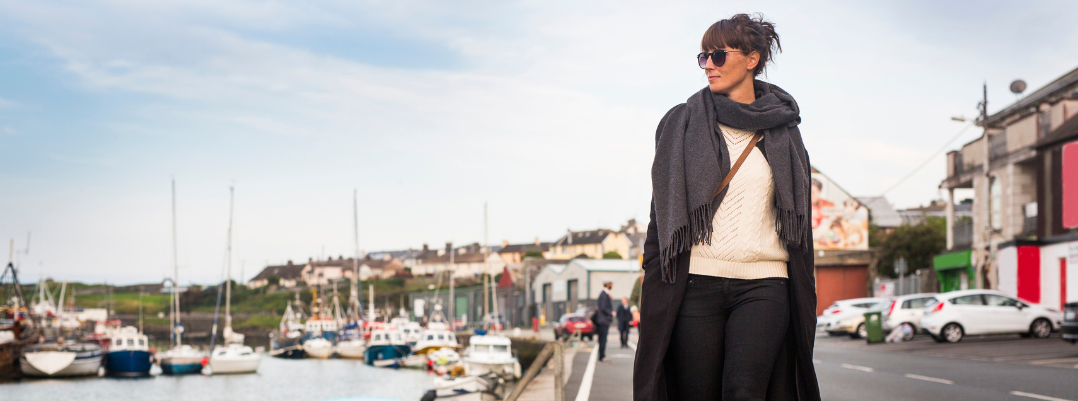 Young woman walking at a harbor in Ireland, one of the best places to travel as a solo female in the U.S. and abroad