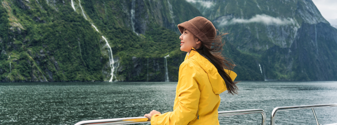 Woman on a ferry at Milford Sound in New Zealand, one of the best places to travel as a solo female in the U.S. and more