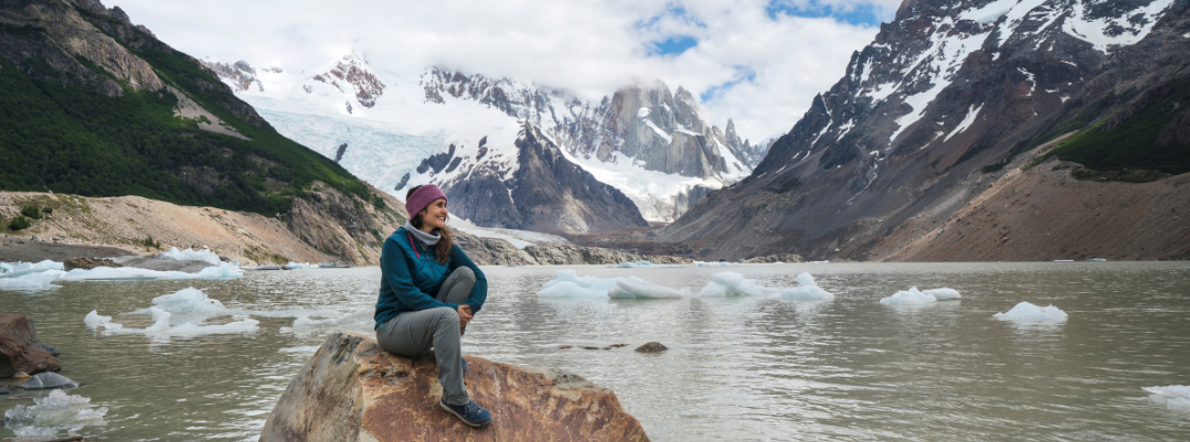 Woman sitting on a rock among mountains in Patagonia, one of the best places to travel as a solo female in the U.S. and more