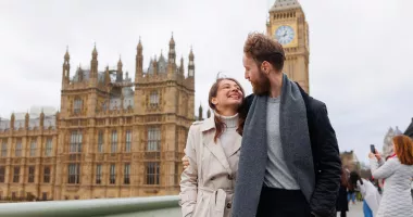 Smiling couple in front of Elizabeth Tower in London, which we tell you more about in our U.K. travel guide.