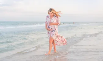 woman holding her belly while walking on the beach and traveling during pregnancy
