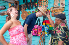 Couple trying on hats at a market during Caribbean travel season