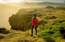 Woman hiking on a cliff in Iceland, one of the best solo travel destinations