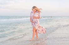 woman holding her belly while walking on the beach and traveling during pregnancy