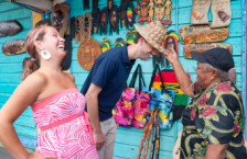 Couple trying on hats at a market during Caribbean travel season