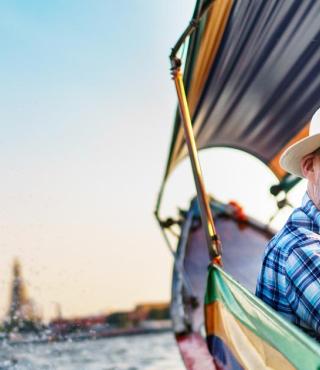 Middle-aged man and his companion handsome blond lady on a boat ride in Bangkok